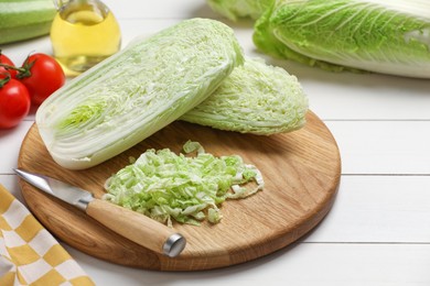 Photo of Fresh Chinese cabbages, knife, tomatoes and oil on white wooden table