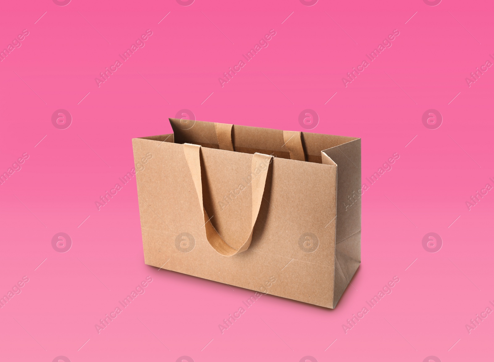 Image of Kraft paper shopping bag on pink background