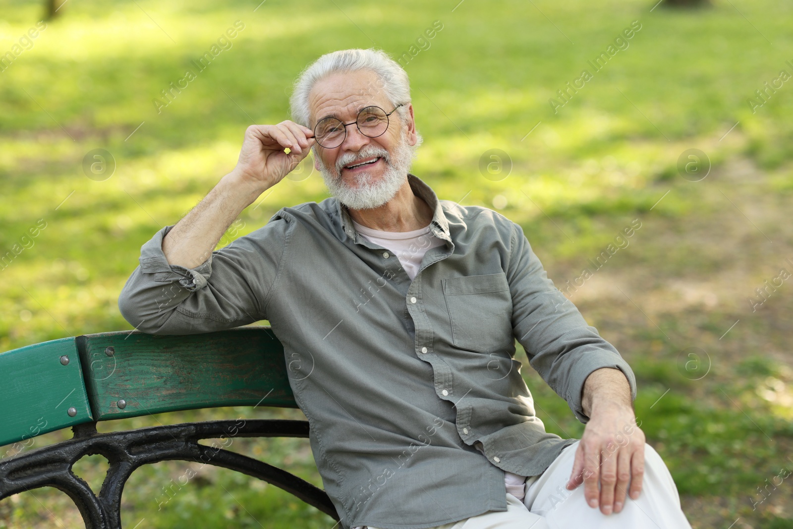 Photo of Portrait of happy grandpa with glasses on bench in park