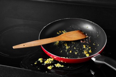 Photo of Dirty frying pan with spatula on cooktop in kitchen