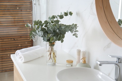 Photo of Fresh eucalyptus branches on countertop in bathroom