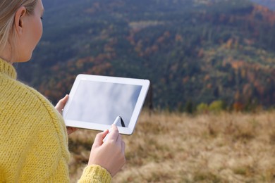 Photo of Young woman drawing with graphic tablet in mountains, closeup