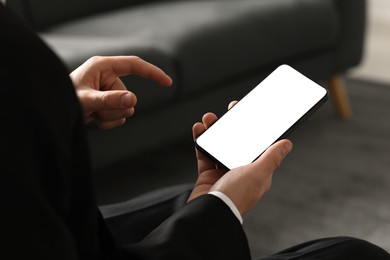 Photo of Man using smartphone with blank screen indoors, closeup. Mockup for design