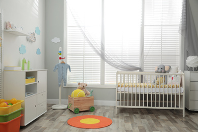 Photo of Stylish baby room interior with crib and toys