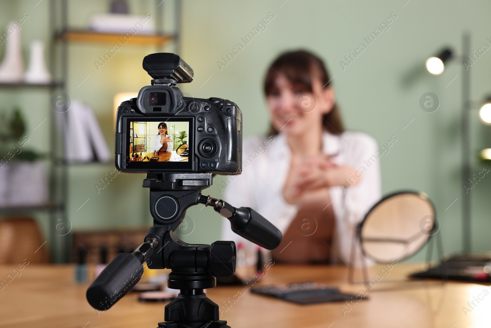 Photo of Beauty blogger recording video at home, focus on camera