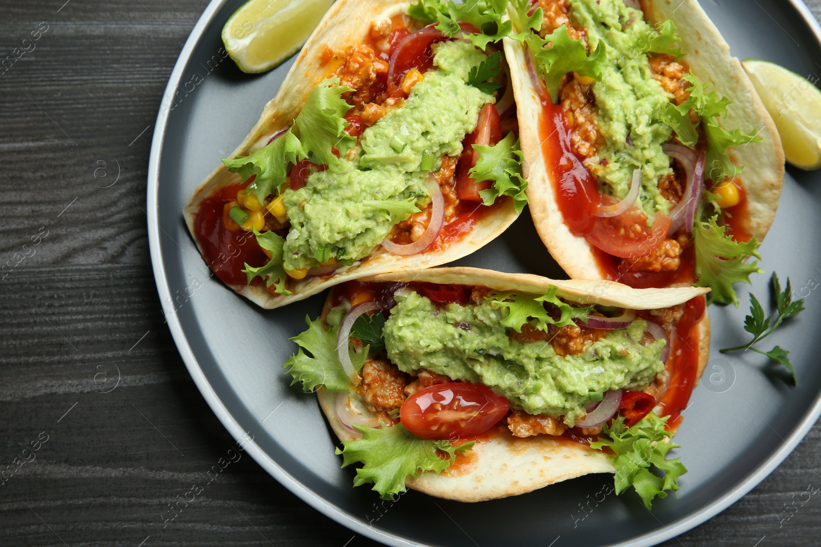 Photo of Delicious tacos with guacamole, meat and vegetables on wooden table, top view