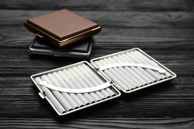 Photo of Stylish leather cigarette cases on black wooden table