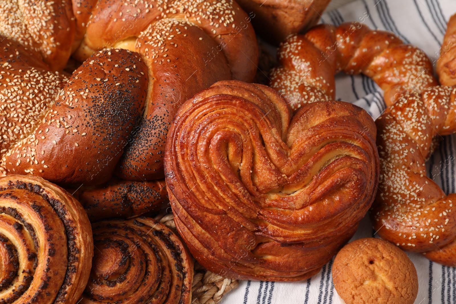 Photo of Different tasty freshly baked pastries on striped tablecloth, above view