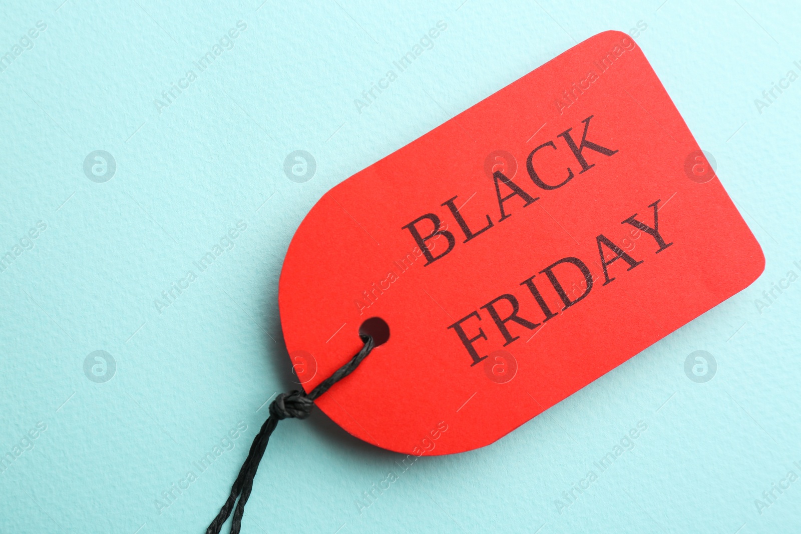 Photo of Red tag with words BLACK FRIDAY on turquoise background, top view