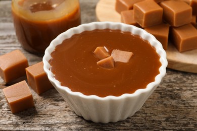 Tasty salted caramel and candies on wooden table