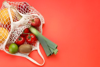 String bag with different vegetables and fruits on red background, top view. Space for text