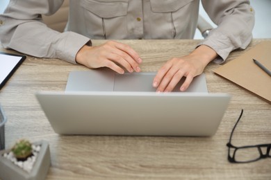 Young woman working with laptop at table, closeup