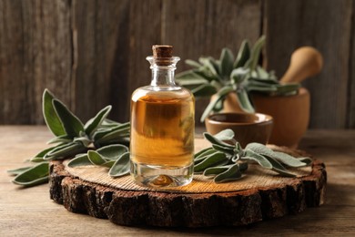Photo of Bottle of essential sage oil and twigs on wooden table