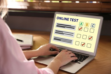 Image of Woman using laptop for online test at table, closeup