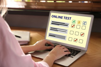 Woman using laptop for online test at table, closeup