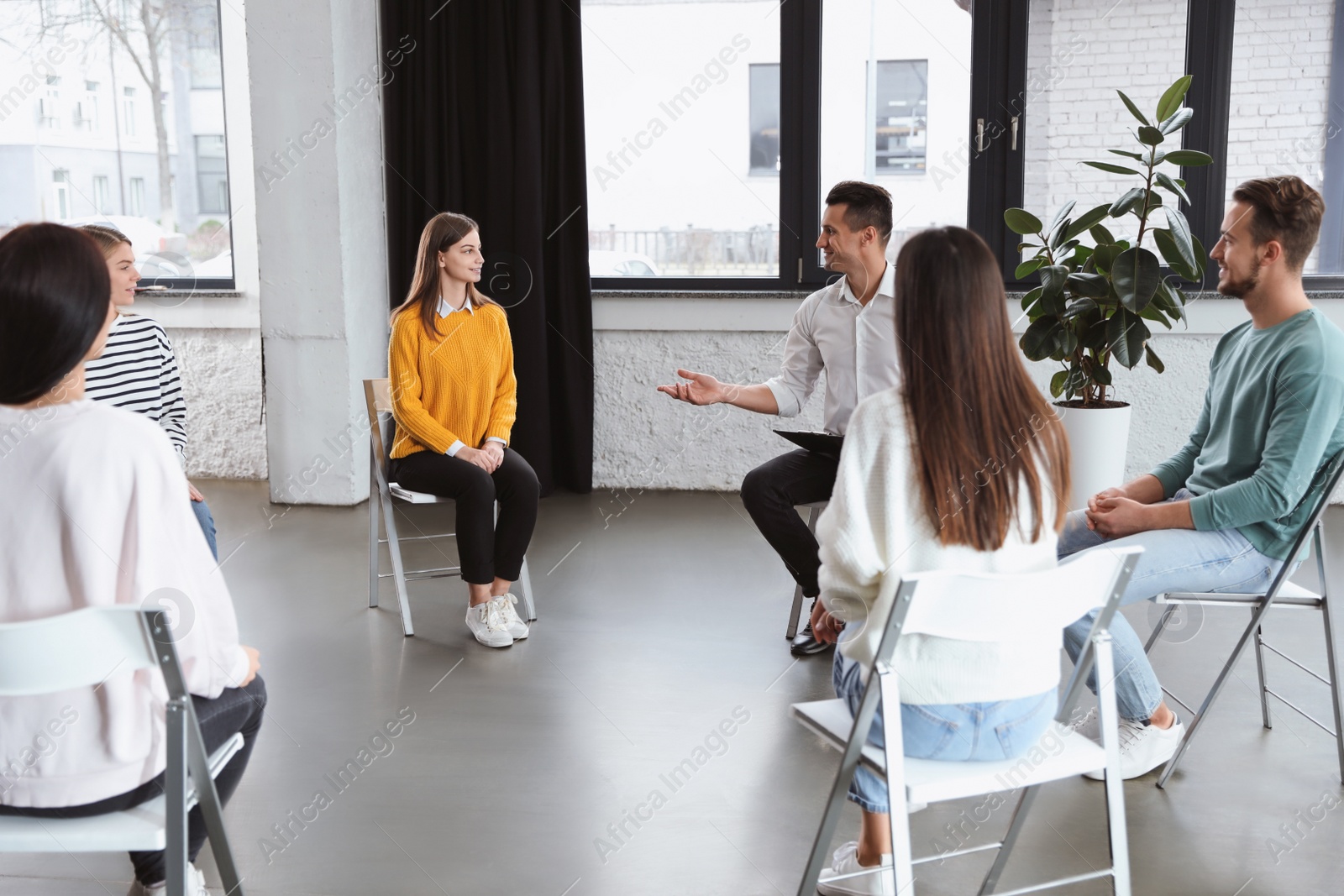 Photo of Psychotherapist working with patients in group therapy session indoors