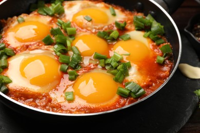 Delicious shakshuka in frying pan on table, closeup