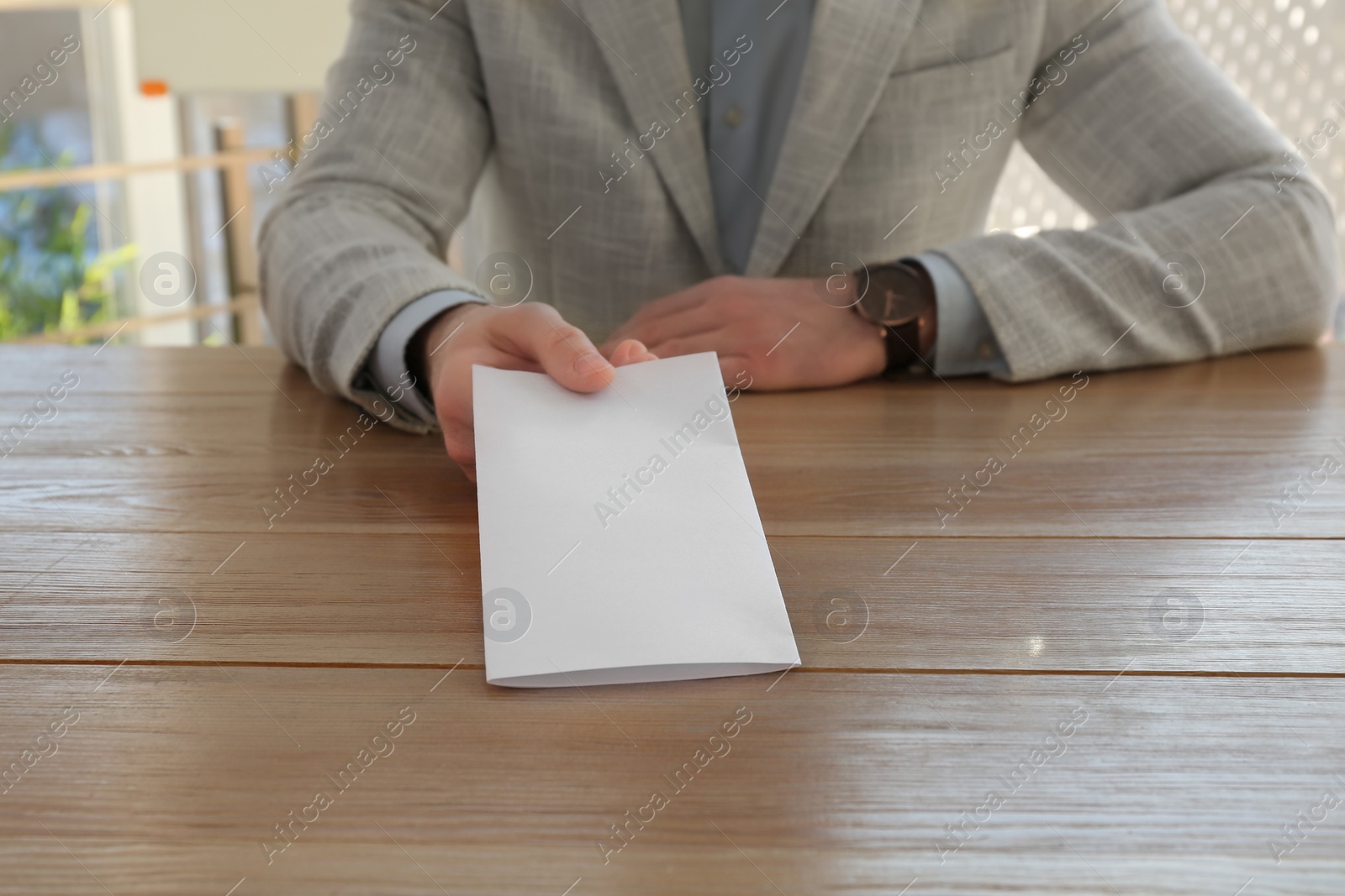 Photo of Employee with resignation letter at table in office, closeup