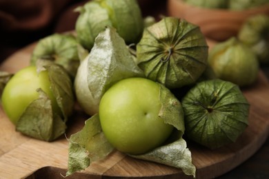 Photo of Fresh green tomatillos with husk on table, closeup