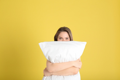 Photo of Young woman with pillow on yellow background