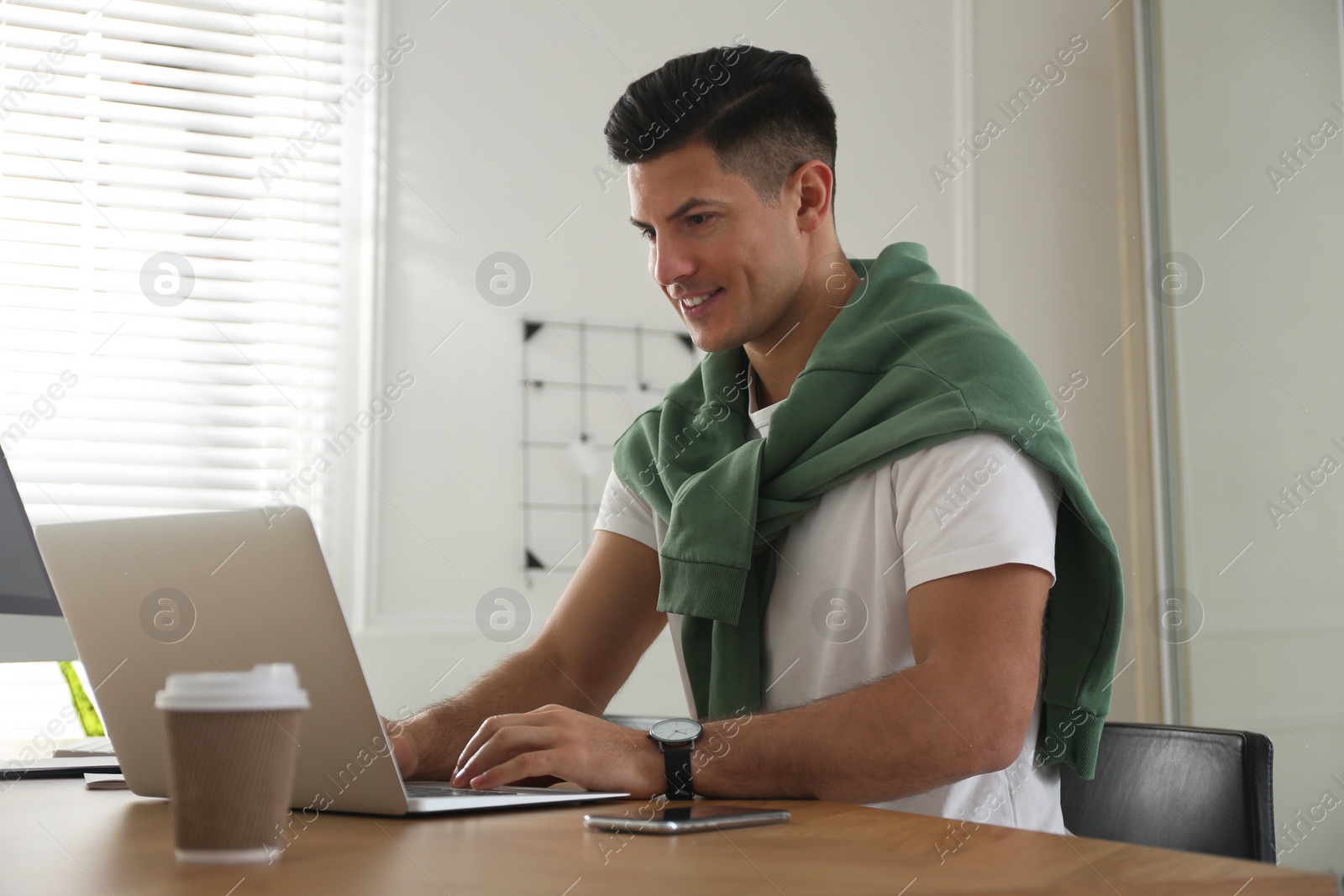 Photo of Freelancer working on laptop at table indoors