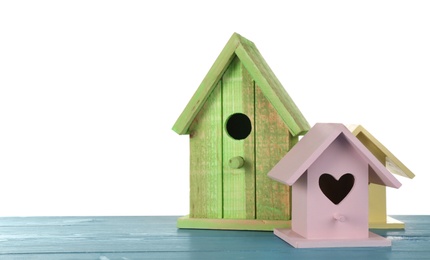 Photo of Three different bird houses on light blue wooden table against white background