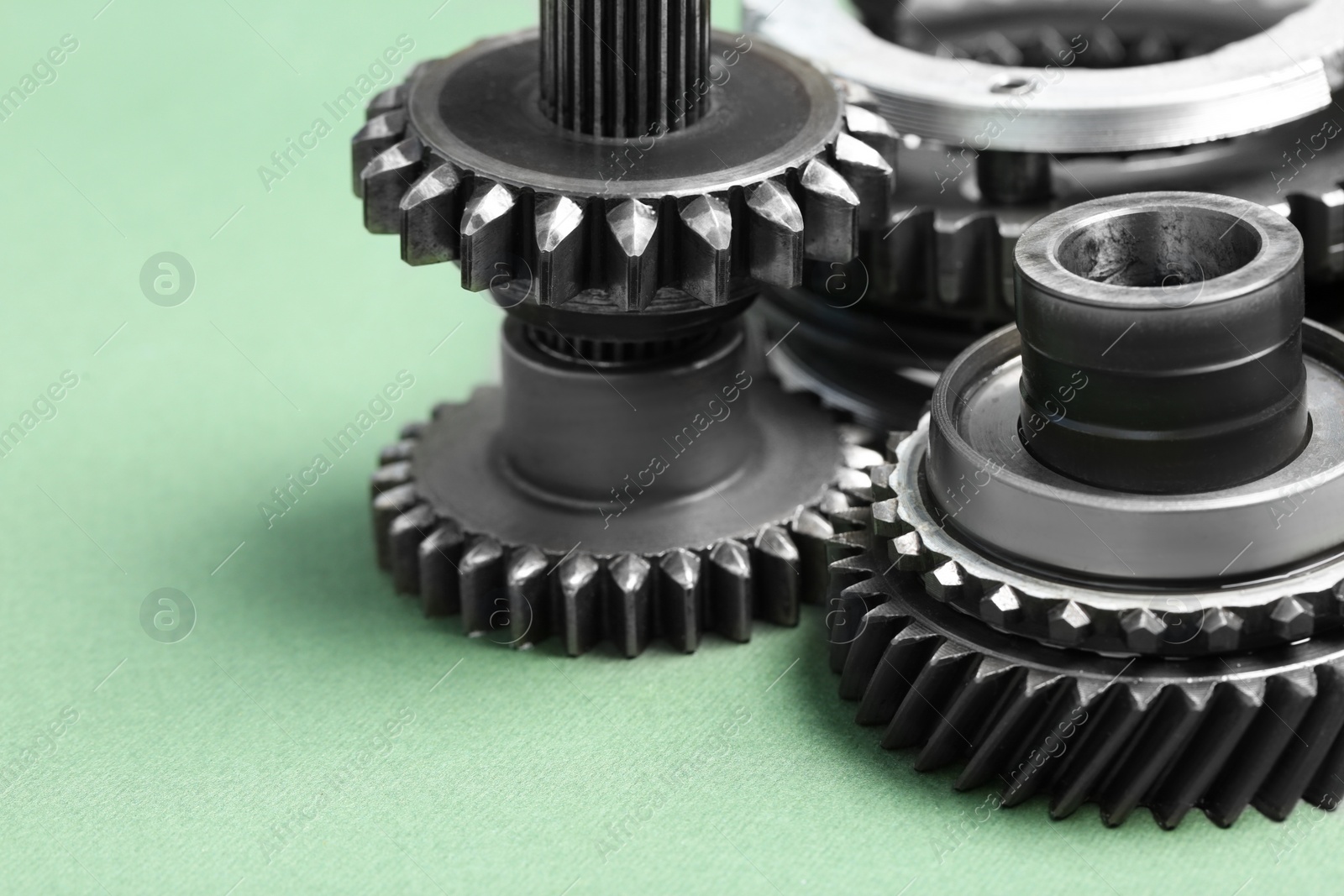 Photo of Different stainless steel gears on light green background, closeup