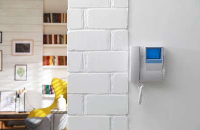 Modern intercom with camera installed on white wall indoors