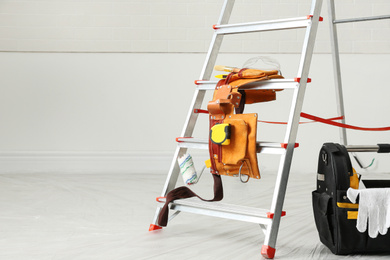 Photo of Stepladder and different tools near wall in room, space for text. Interior renovation