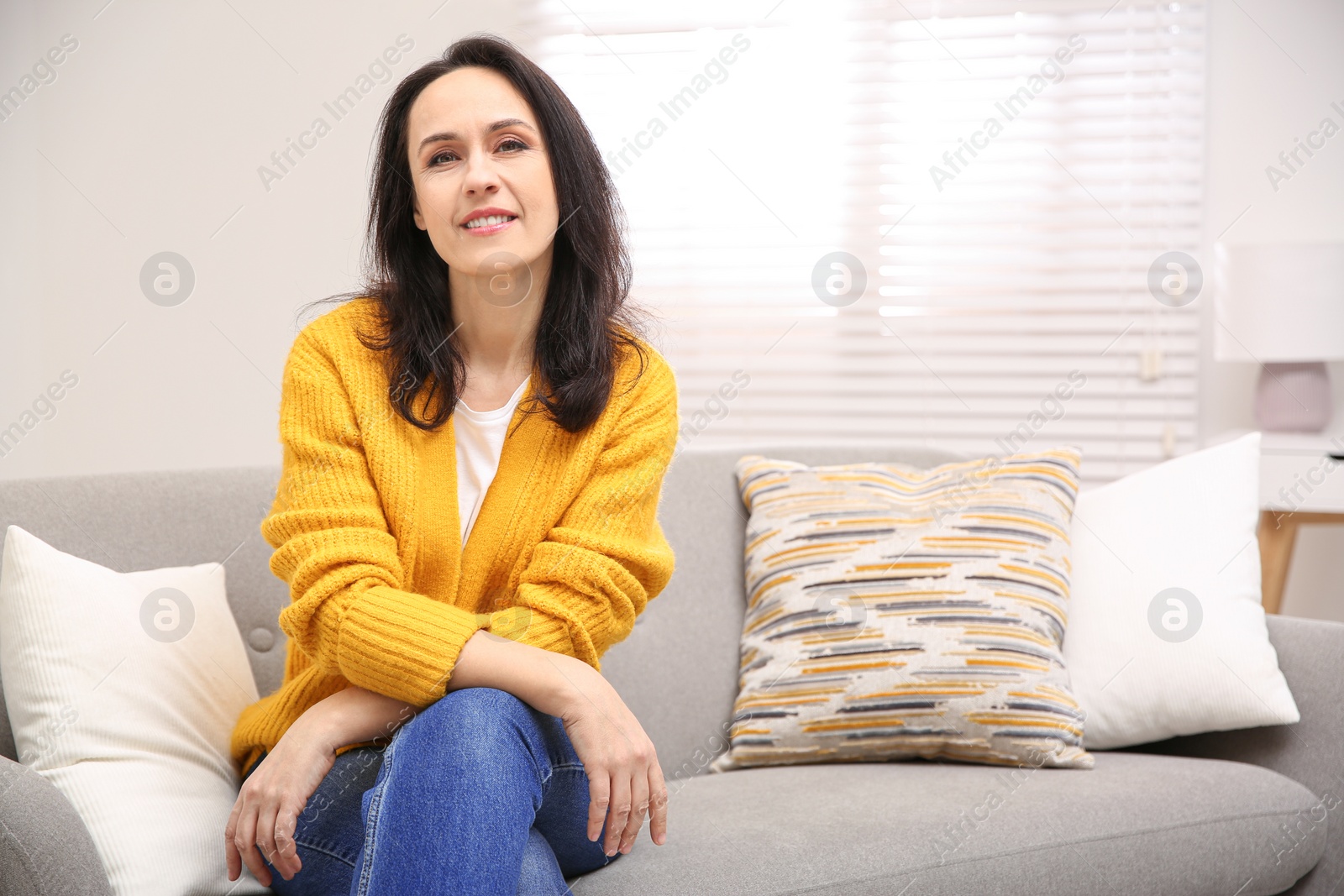 Photo of Beautiful mature woman on sofa at home. Space for text