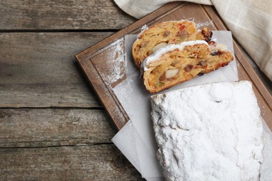 Traditional Christmas Stollen with icing sugar on wooden table, flat lay. Space for text