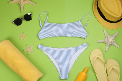Photo of Flat lay composition with swimsuit and beach accessories on green background