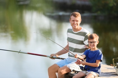 Dad and son fishing together on sunny day