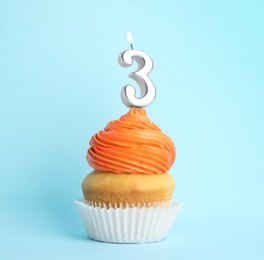 Photo of Birthday cupcake with number three candle on blue background