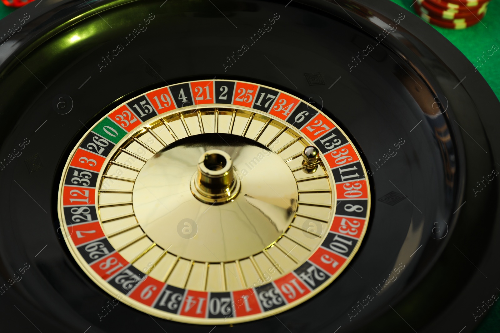 Photo of Roulette wheel with ball on green table, closeup. Casino game