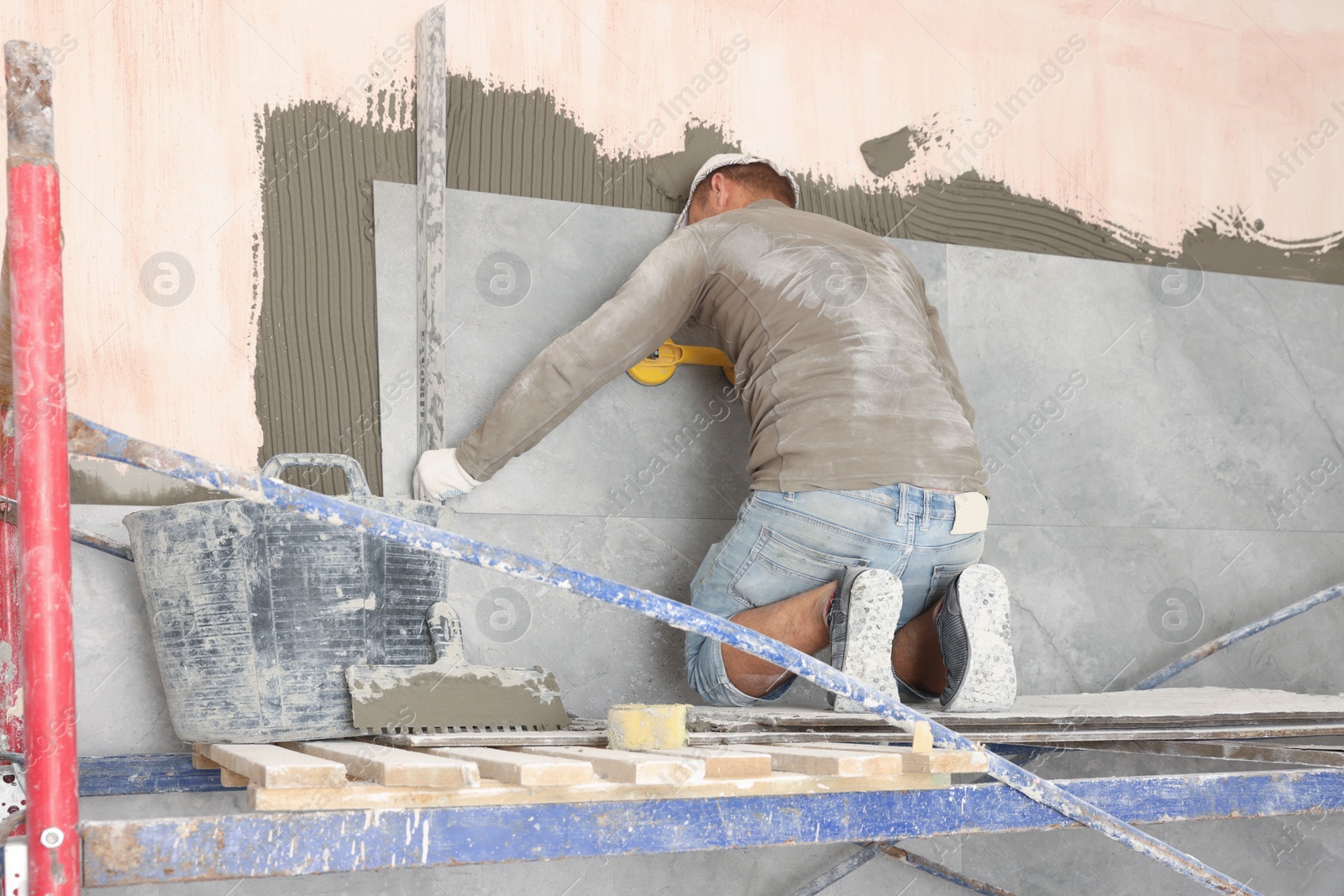 Photo of Worker installing new wall tile in room. Prepared for renovation