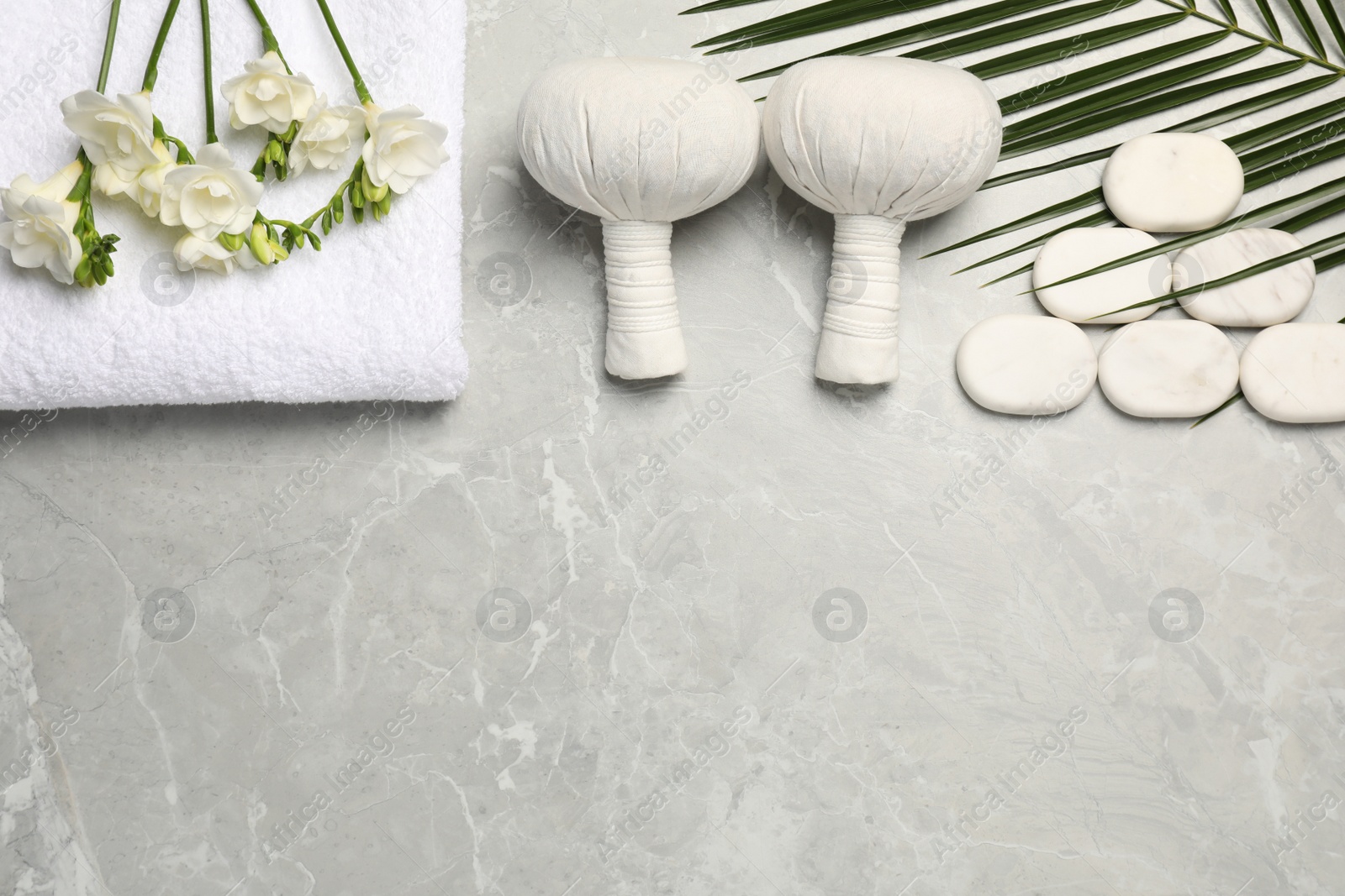 Photo of Spa bags, stones and freesia flowers on light gray marble table, flat lay. Space for text