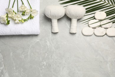 Spa bags, stones and freesia flowers on light gray marble table, flat lay. Space for text