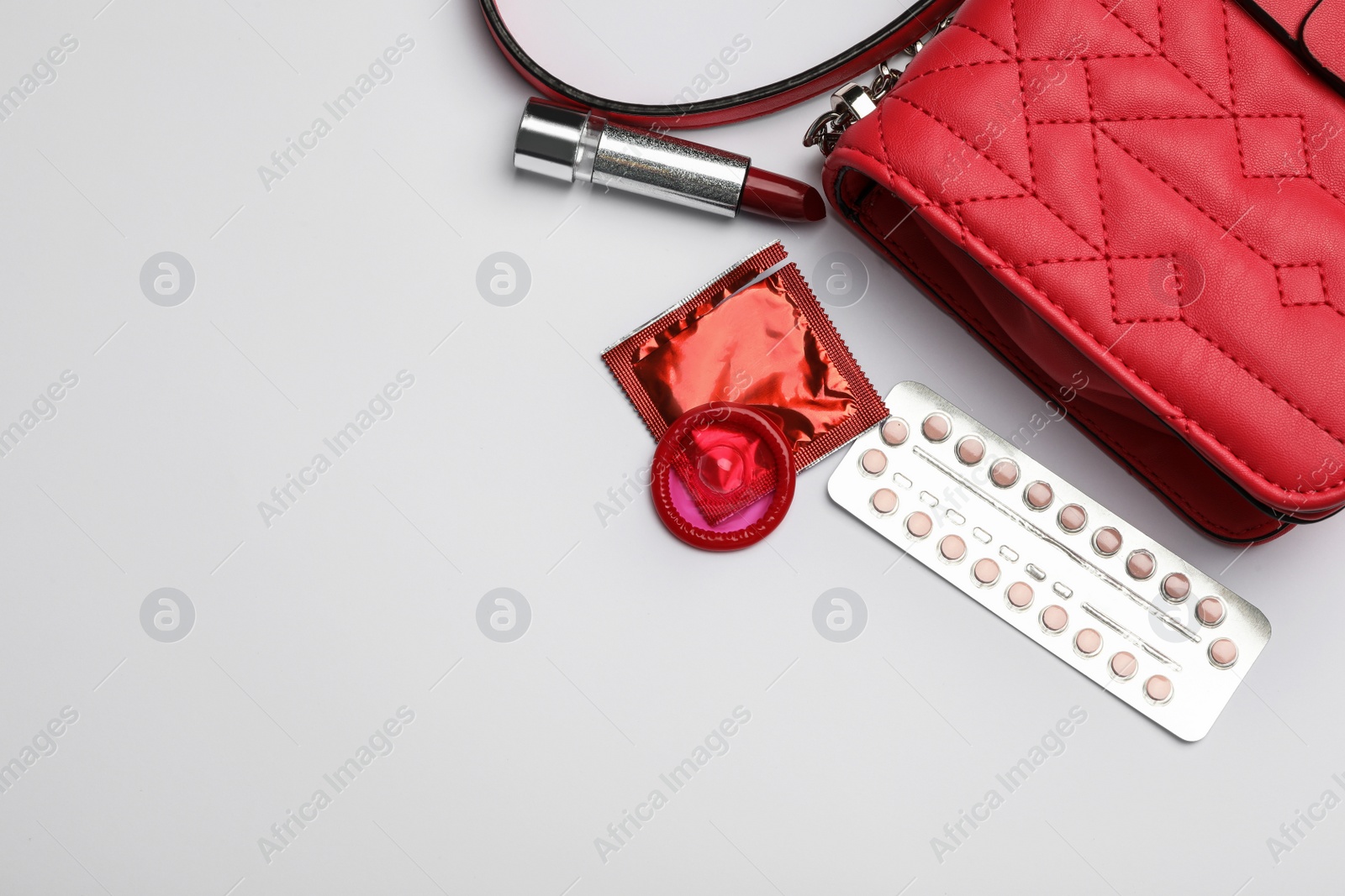 Photo of Flat lay composition with birth control pills and condoms on light background, space for text. Safe sex concept