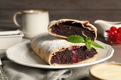 Delicious strudel with cherries and poppy seeds on grey table, closeup