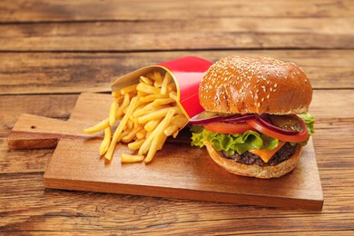 Photo of Tasty burger and French fries on wooden table. Fast food