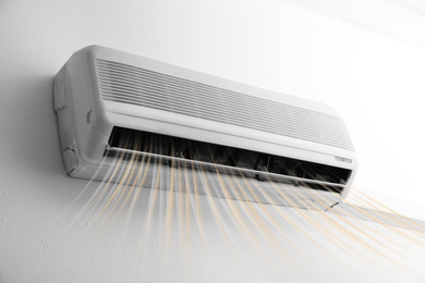 Modern air conditioner on white wall indoors