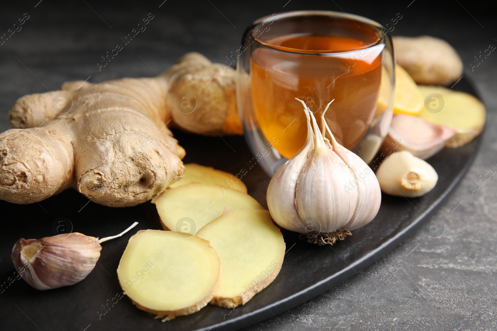 Photo of Fresh garlic and other natural cold remedies on grey table