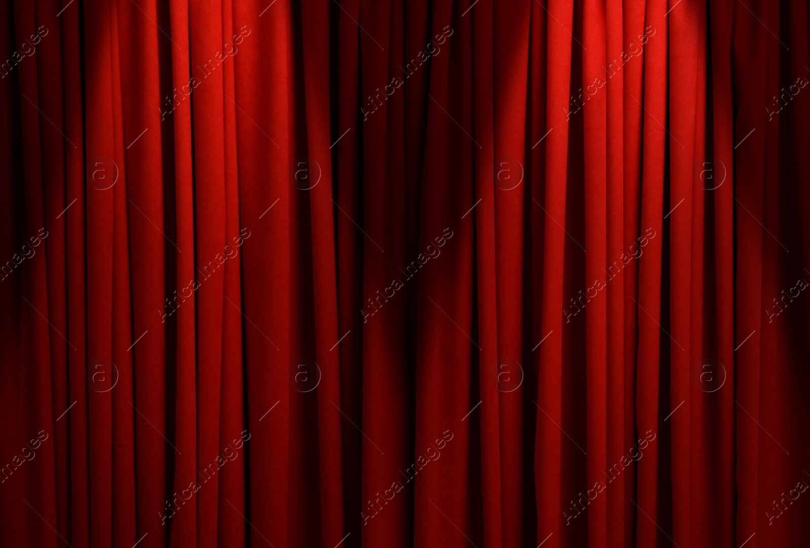 Image of Spotlights illuminating closed red stage curtains. Start of performance 