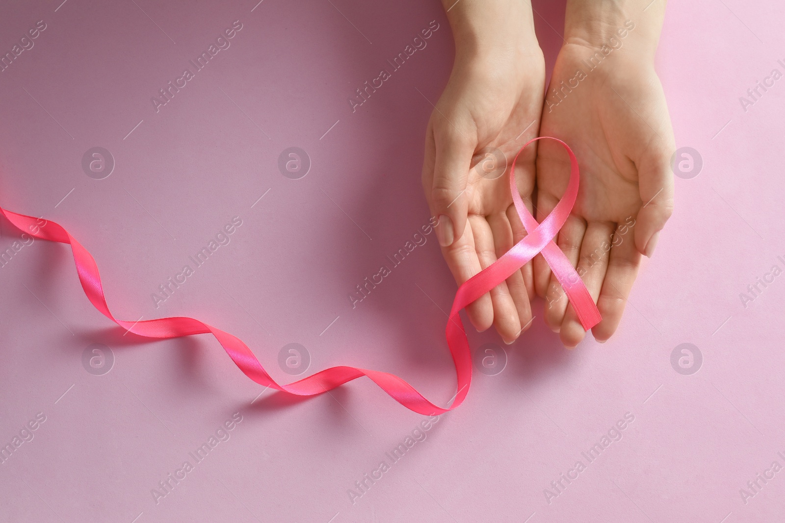 Photo of Woman holding pink ribbon on color background, top view. Breast cancer awareness