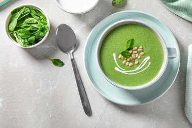 Photo of Cup of healthy green soup with fresh spinach served on light table, flat lay