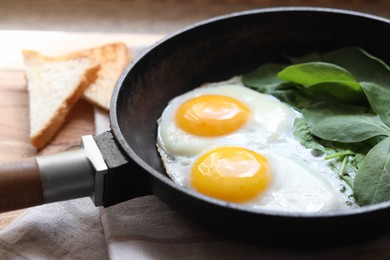 Photo of Delicious fried egg with spinach served on wooden table, closeup