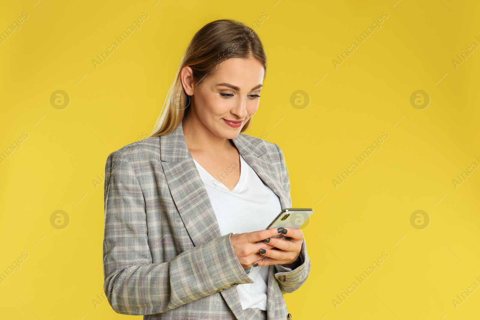 Photo of Beautiful woman using smartphone on yellow background