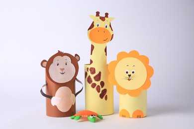 Photo of Toy monkey, giraffe and lion made from toilet paper hubs with plasticine turtle on white background. Children's handmade ideas