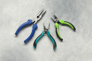 Photo of Different pliers on grey textured table, flat lay